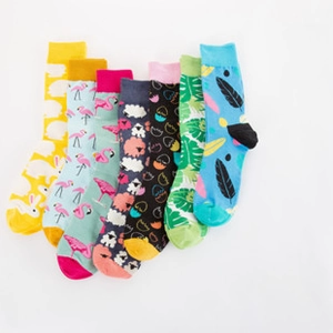 Flat lay set of seven colorful crew socks featuring vibrant animal and leaf patterns