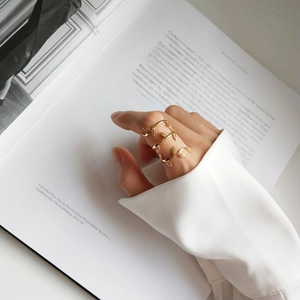Close-up of golden leaf multi-layer wrap ring worn against an artistic book background