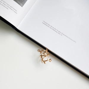 Detailed view of a gold leaf spiral ring draped over a book page for elegant display