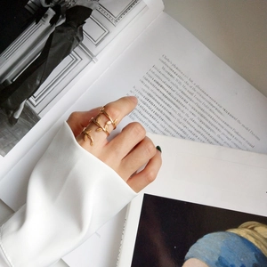 Detailed view of a gold leaf wrap ring worn on a finger against an artistic book background