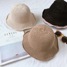 Flat lay of hollow-out knit bucket hats in beige, khaki, and black with wavy brims