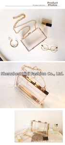 Macro view of clear acrylic clutch bag showing gold metal edges and removable chain strap