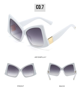 Detail view of white bow-shaped oversized sunglasses with golden hinge and gradient lenses