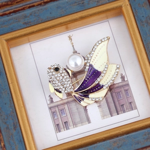 Detailed view of goldfish brooch with gradient purple enamel and large white pearl inlay