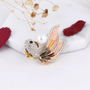 Detail of goldfish brooch with pearl inlay and pink enamel gradient tail on marble