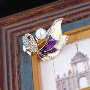 Macro detail of goldfish brooch showing colorful enamel tail and pearl centerpiece
