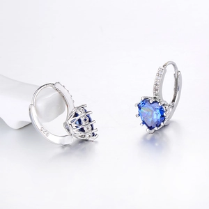 Detailed macro view of 925 silver hoop earrings with blue heart-shaped cubic zirconia