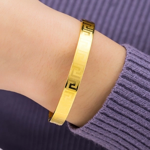 Bracelet jonc doré avec motif grec classique porté sur le poignet d'une femme