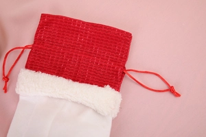 Détail d'un sac à vin de Noël en tissu à mailles rouges avec bordure en peluche blanche