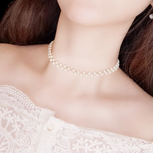 Elegant pearl choker necklace with gold chain shown on a model with white lace dress