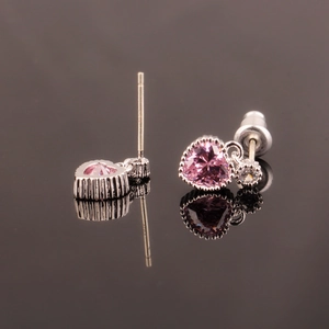 Macro shot of silver heart earrings with pink corundum and transparent stones