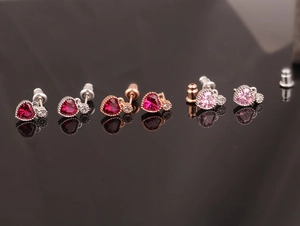 Detailed macro view of heart-shaped ruby earrings in silver and rose gold finishes