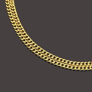 Macro shot of layered gold plated Cuban link chains with polished metallic finish