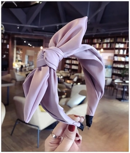 Detail view of a light purple oversized fabric bow headband with black non-slip ends