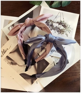 Detailed view of satin bow headbands in dusty pink and blue on a fashion magazine