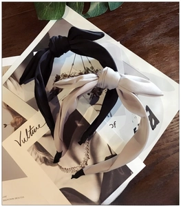 Detail of black and light grey fabric bow headbands on a textured magazine background