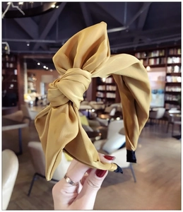 Close-up of yellow satin fabric knot and texture on the wide bow headband