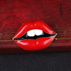 Vue macro d'une broche lèvres en émail rouge et bord doré sur un coffret cadeau