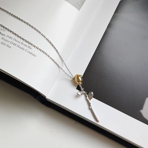Macro detail of a 925 silver rose pendant with gold blossom on a delicate cross chain