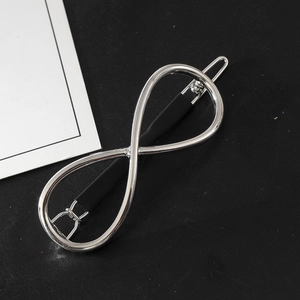 Polished silver infinity symbol hair clip on black background with macro detail