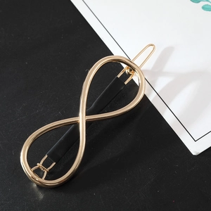 Detail of infinity symbol hair clip with golden finish and black matte bar design