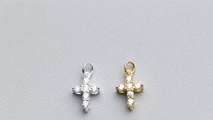 Detailed view of silver and gold plated cross charms with inlaid cubic zirconia crystals