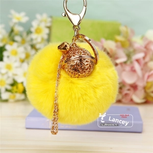 Détail d'un pompon jaune vif en fausse fourrure avec breloque ajourée en or rose