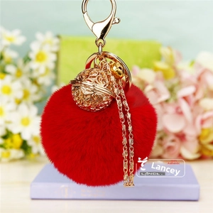 Détail du porte-clés pompon rouge avec clochette florale dorée et petit grelot élégant
