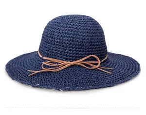 Detail of navy blue straw sun hat featuring a fine brown string bow and woven texture