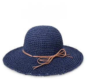 Detail of navy blue woven straw sun hat featuring a wide brim and brown ribbon bow decoration