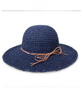 Close-up of dark blue hand-woven straw hat with brown leather bow and fine texture