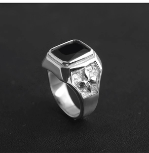 Macro detail of men's vintage steel ring with black gemstone and fleur-de-lis carving