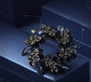 Detail view of crystal and AAA rhinestone floral brooch in silver-black metal finish