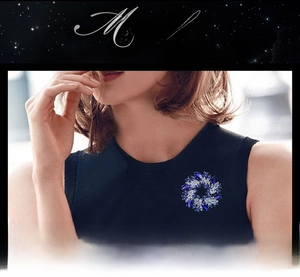 Detailed view of flower-shaped brooch with blue crystals on a black sleeveless top