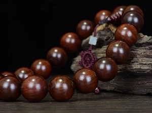 Macro shot of polished dark brown Rosewood prayer beads with natural wood grain texture