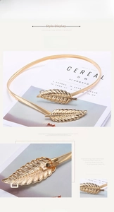 Macro detail of elastic gold leaf waist belt featuring an adjustable alloy strap