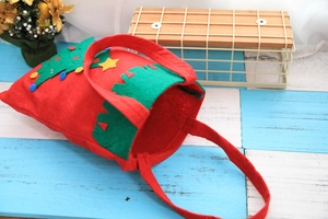 Detail of red felt Christmas gift bag featuring thick hand-stitched green tree pattern