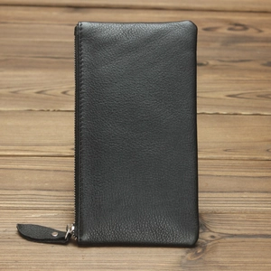 Detailed view of black crazy horse leather wallet with premium metal zipper on wood surface