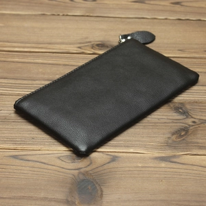 Detail of black leather wallet texture with silver zipper on rustic wooden background