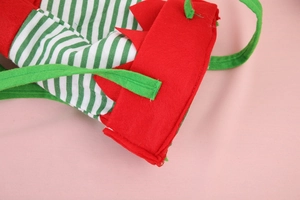 Dettaglio di un sacchetto regalo di Natale rosso con accenti a righe verdi e manici in feltro