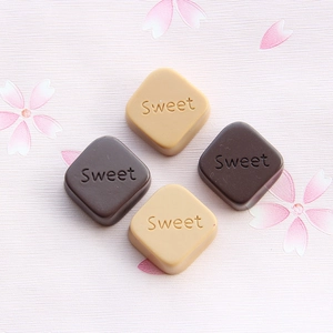 Macro shot of square resin chocolates embossed with Sweet on cherry blossom fabric