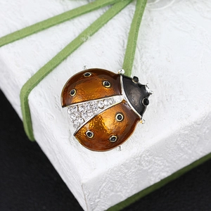 Macro detail of ladybug brooch with orange enamel and sparkling crystal rhinestones