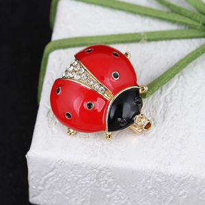 Macro shot of ladybug brooch with red enamel, white crystals, and gold-tone finish