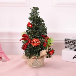 Mini green Christmas tree tabletop decor with red bows and burlap base for festive home