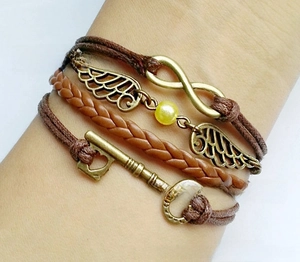 Detail of multi-layer brown braided bracelet with vintage bronze charms on a wrist