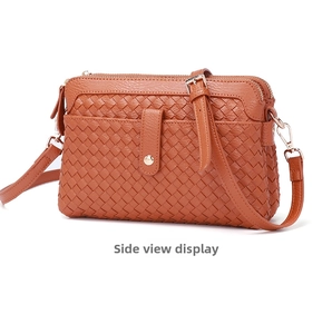 Close-up of brown woven leather crossbody bag featuring dual zipper pockets and gold hardware