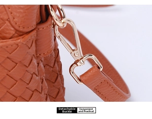 Detail of detachable light gold buckle on a brown woven leather crossbody bag