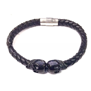 Détail du bracelet en cuir tressé noir pour homme avec breloques crâne et fermoir aimanté