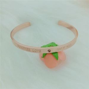 Macro detail of rose gold C-shaped open bangle with engraved Forever Love and diamond