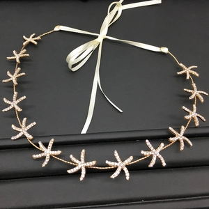 Detail of golden starfish bridal headband with sparkling rhinestones and white silk ribbon